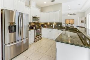 a kitchen with white cabinets and a stainless steel refrigerator at Modern home w screened pool, hot tub, & comm amenities! in Naples