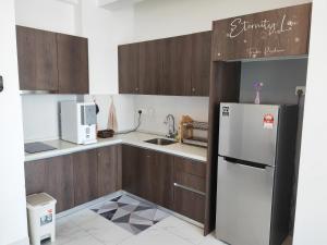 a kitchen with wooden cabinets and a white refrigerator at Troika Residence Kota Bharu @ Eternity Live-1B4pax in Kota Bharu