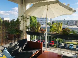a patio with a couch and an umbrella on a balcony at Alt Treptow Fashion HQ in Berlin