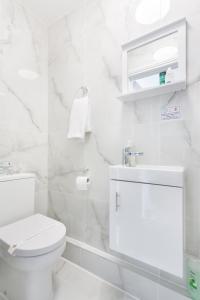 a white bathroom with a toilet and a sink at Studio9 Rooms - Next to Emirates Stadium - Budget Rooms with Shared Bathroom in London