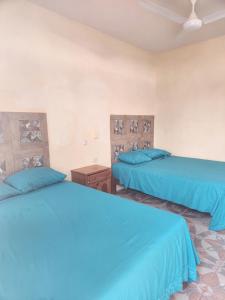2 letti in una camera con lenzuola blu di Posada Las Palmas a Coyuca