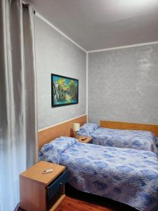 1 Schlafzimmer mit 2 Betten, einem Tisch und einem Gemälde in der Unterkunft AFFITTACAMERE DOLCE SOGNO in Cherasco