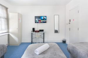 a room with two beds and a table and a tv at Studio9 Rooms - Next to Emirates Stadium - Budget Rooms with Shared Bathroom in London
