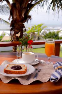 a table with a plate of cake and a cup of orange juice at Casa Cancun Eventos e Hotel Boutique in Penha