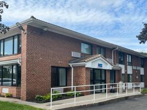 a brick building with a fence in front of it at Studio 6 Suites East Syracuse NY Airport in East Syracuse