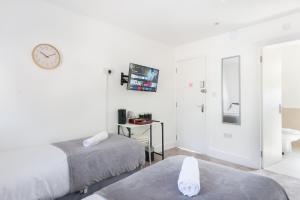 a white room with two beds and a clock on the wall at Studio9 Rooms - Next to Emirates Stadium - Budget Rooms with Shared Bathroom in London