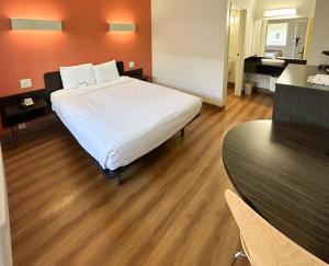 a bedroom with a white bed and a wooden floor at Studio 6 Suites - Riverside, CA South in Riverside
