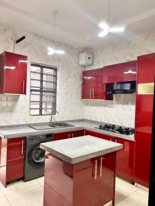 a red kitchen with red cabinets and a sink at Homely Shortlet Apartment LBS, AJAH in Lagos