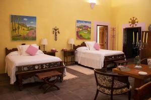 a bedroom with two beds and a table and a desk at Hacienda de Teresa in Itzamatitlán