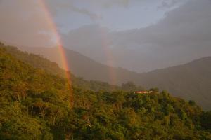 Un arc-en-ciel au milieu d'une forêt avec une maison dans l'établissement Mundo Nuevo Eco Lodge, à Minca