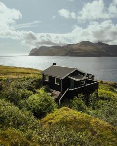 a small black house on the side of a lake at Cottage with stunning view of the sea and islands. in Leynar