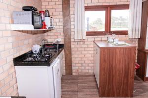 a kitchen with a sink and a stove top oven at Bangalo da santa in Guarda do Embaú