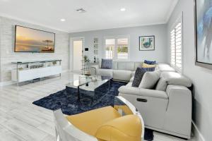 una sala de estar con muebles blancos y sillas amarillas. en The Gardens - Luxury Retreat with Pool & Game Room, en Miami Gardens