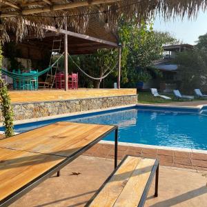 a wooden table next to a swimming pool at Villa Coiros Bici, Hospedaje y Bienestar in Tonatico