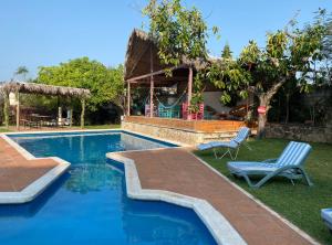 a swimming pool with two chairs and a house at Villa Coiros ECOFRIENDLY suites & villas in Tonatico