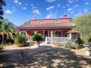 una casa rosa con una valla blanca en Casa rural en el campo con animales, piscina y barbacoa, en Almodóvar del Río