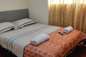łóżko z dwoma ręcznikami i pilotem w obiekcie Casa Familiar Guadalupe Cusco w Cuzco