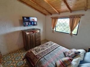 - une chambre avec un lit et une télévision dans l'établissement Mountain Cabin - Nature and Relax, à Fúquene