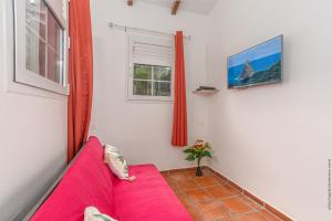 a red couch in a room with a window at Bungalow avec piscine au cœur de la campagne Vert in Sainte-Marie