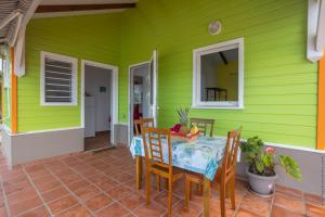 ein grünes Haus mit einem Tisch und Stühlen in der Unterkunft Bungalow avec piscine au cœur de la campagne Vert in Sainte-Marie