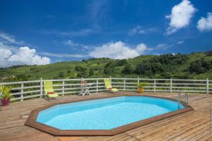una piscina en una terraza con 2 sillas y una persona en Bungalow avec piscine au cœur de la campagne Vert, en Sainte-Marie