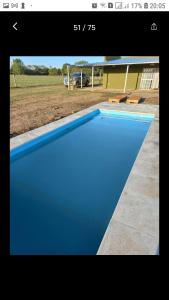 a blue swimming pool in front of a house at El retiro, casa de campo in San Antonio de Areco