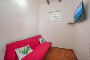 a red couch in a room with a flat screen tv at Bungalow avec piscine au cœur de la Campagne Oge in Sainte-Marie