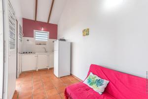 a red couch in a kitchen with a refrigerator at Bungalow avec piscine au cœur de la Campagne Oge in Sainte-Marie