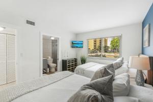 Un dormitorio blanco con dos camas y un sofá. en 10 mins from Pompano Beach! With pool access, en Pompano Beach 18 fotos más