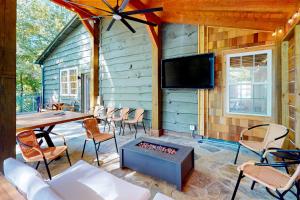 a patio with a table and chairs and a tv on a wall at River Rock Cottage in Boone