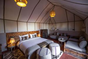 um quarto com uma cama e um sofá numa tenda em Golden Camp & Oasis em Merzouga
