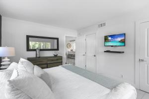 1 dormitorio blanco con 1 cama y TV de pantalla plana en Expansive wiith pool access, 10 mins from Pompano Beach en Pompano Beach