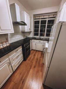 a kitchen with white cabinets and a black refrigerator at Cosy 2 bedroom apartment in Swiss Cottage. in London