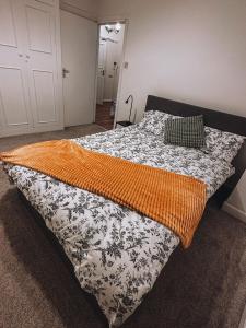 um quarto com uma cama com um cobertor laranja em Cosy 2 bedroom apartment in Swiss Cottage. em Londres