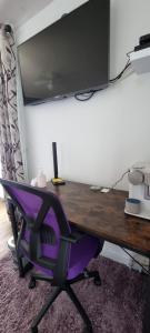 a desk with a computer monitor and a purple chair at La Petite Locherie in Oradour-Saint-Genest
