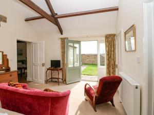 uma sala de estar com um sofá vermelho e cadeiras em Sheep Pen Cottage em Durham