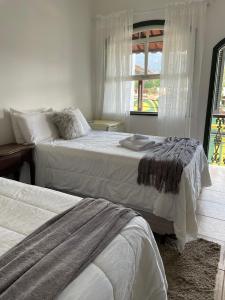 a bedroom with two beds and a window at Pousada Encanto de Tiradentes in Tiradentes
