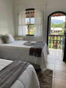 a bedroom with two beds and a large window at Pousada Encanto de Tiradentes in Tiradentes