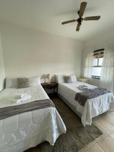 a bedroom with two beds and a ceiling fan at Pousada Encanto de Tiradentes in Tiradentes
