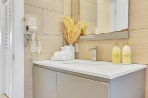Un baño con un lavabo blanco y un espejo. en Sunny Pompano Beach with pool access, en Pompano Beach 23 fotos más