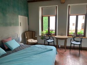 a bedroom with a bed and two chairs and a table at La Cense - Mélin in Jodoigne