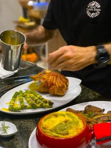 een man die voedsel bereidt op een tafel met borden voedsel bij Mont Carpe Diem 