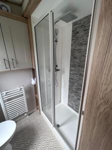 a glass shower door in a bathroom with a tile floor at Sandy Toes, Padstow in Padstow