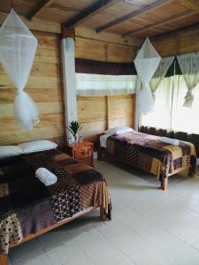 Topche, Centro Ecoturístico في Lacanjá: سريرين في غرفة بجدران خشبية