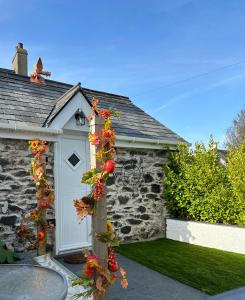 a house with a white door with flowers on it at White Mermaid Cottage Anglesey Holidays in Newborough