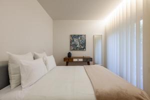 a white bedroom with a large bed with white pillows at Casa do Alcaide - Minhos Guest in Braga