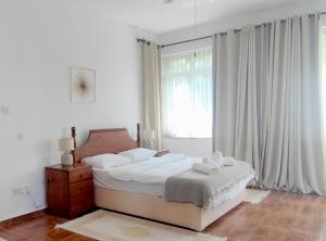 a white bedroom with a bed and a window at Babil Bahceleri - Gardens of Babel in Lapithos