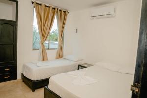 two beds in a room with a window at Caribbean Town Tolu in Tolú