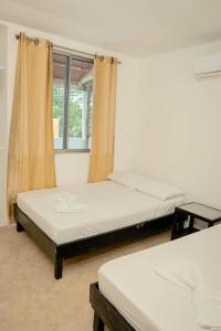 2 camas en una habitación con ventana en Caribbean Town Tolu, en Tolú