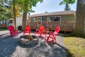 a group of red chairs sitting around a fire pit at Higgins Lake Cottage with Private Fire Pit and Grill! in Roscommon
